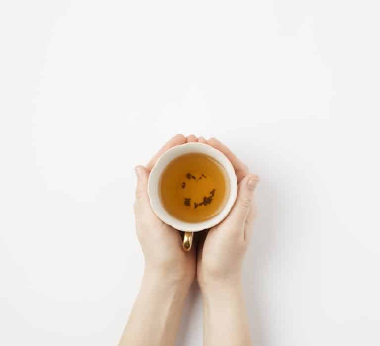 Tasse de thé tenue à deux mains, vue du dessus
